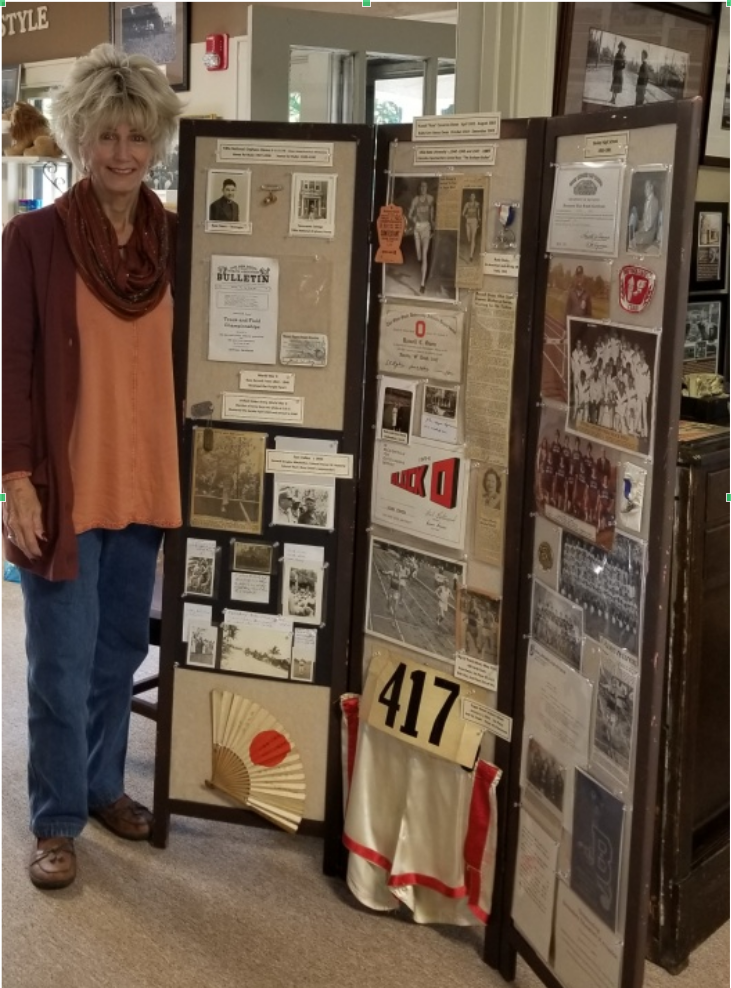Nancy Owen-Hawkins standing by a portion of the materials she provided of her father, Russ, and her mother, Ruby.